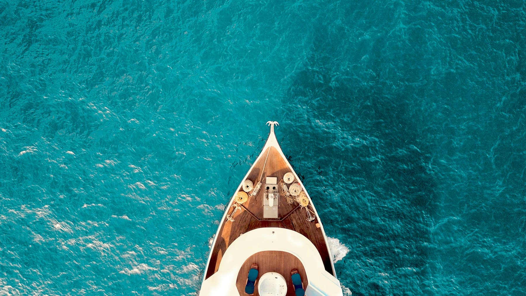 Aerial view of a yacht bow cutting across turquoise water
